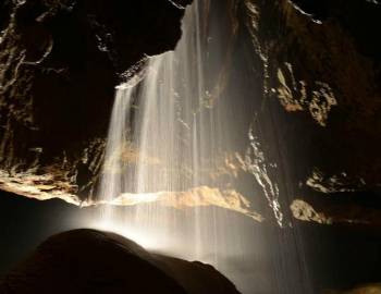 Tuckaleechee Caverns in Townsend, TN an underground waterfall in a cave, lit from below 